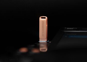 A rose gold colored USB drive with the DJ Techtools logo on it plugged into a CDJ