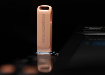 A rose gold colored USB drive with the DJ Techtools logo on it plugged into a CDJ